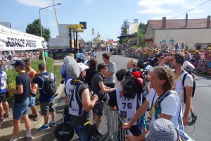 TV crews and photographers await the arrival of the peloton in the Mixed Zone beyond the finish line