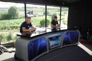 Off-air: NBCSN Analyst Christian Vandevelde and Host Paul Burmeister in studio, front of glass panels treated with Rosco polariser system to darken the bright sunlit background outside